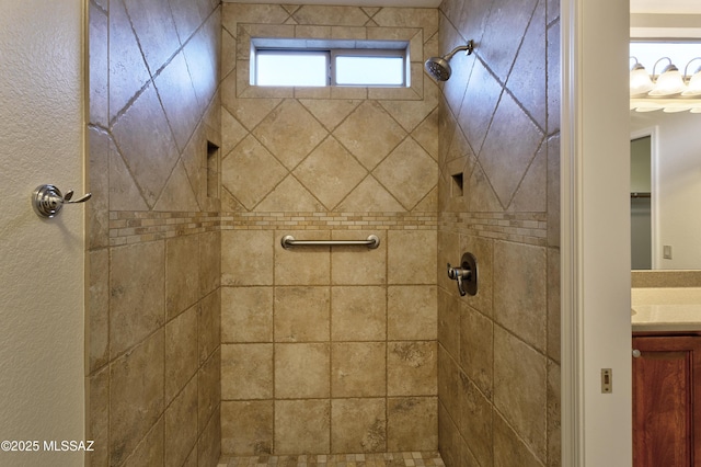 bathroom featuring tiled shower and vanity