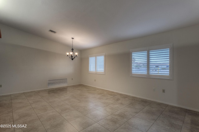 empty room with light tile patterned floors and an inviting chandelier