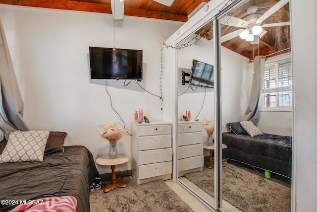 carpeted bedroom with ceiling fan, lofted ceiling with beams, and wooden ceiling