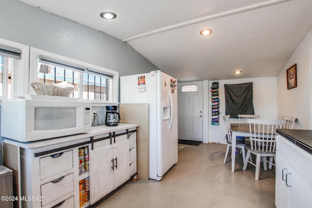 kitchen with lofted ceiling, white cabinetry, and white appliances