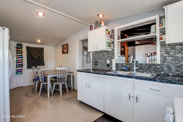 kitchen with white cabinetry, sink, tasteful backsplash, white fridge, and vaulted ceiling