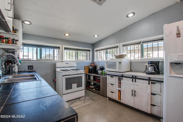 kitchen with a healthy amount of sunlight, white appliances, sink, and vaulted ceiling