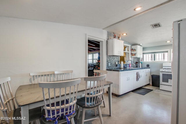 kitchen with white cabinets, white range, tasteful backsplash, and sink