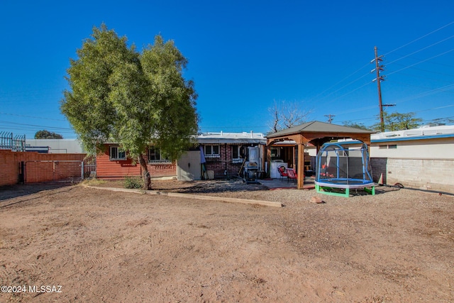 rear view of house with a gazebo and a trampoline