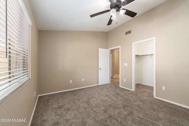 unfurnished bedroom featuring carpet flooring, a spacious closet, a closet, and ceiling fan