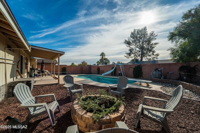 view of pool featuring a diving board, a patio area, and a water slide