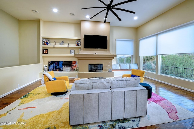 living room with hardwood / wood-style floors, ceiling fan, and built in shelves