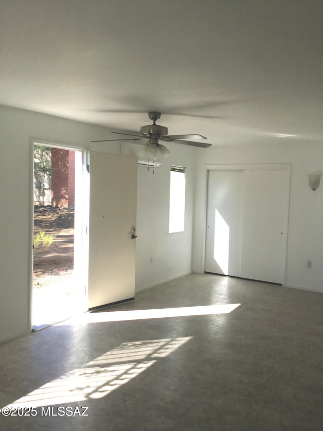 spare room featuring plenty of natural light, concrete floors, and ceiling fan