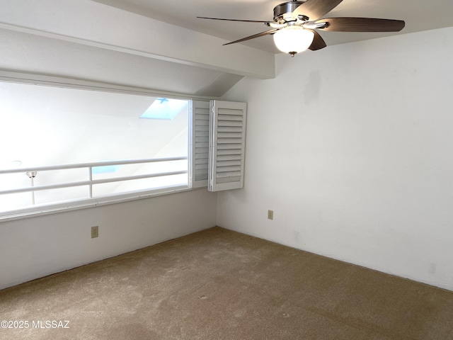 spare room with a ceiling fan, carpet flooring, and vaulted ceiling with beams