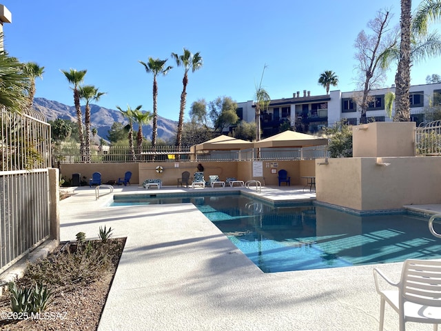 community pool featuring a patio, fence, and a mountain view