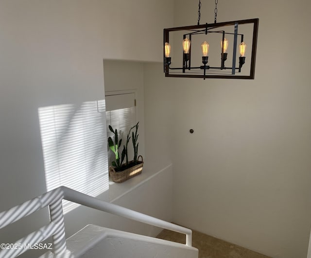 stairs with carpet flooring and an inviting chandelier