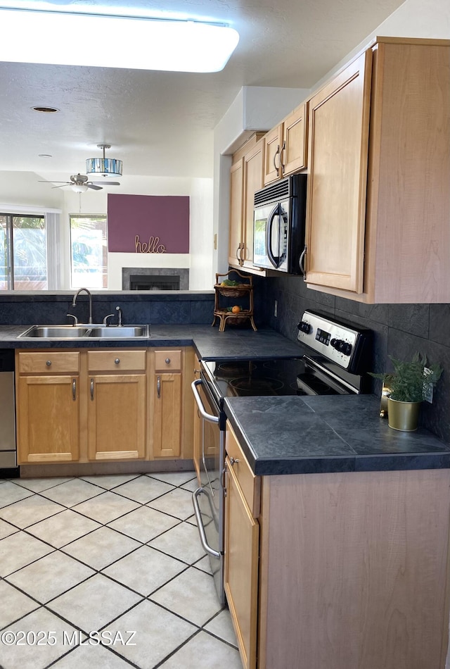 kitchen with appliances with stainless steel finishes, dark countertops, a sink, and decorative backsplash