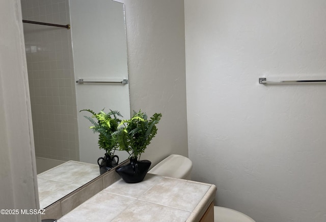 bathroom with a textured wall, vanity, and toilet