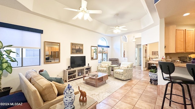 tiled living room featuring a tray ceiling and ceiling fan