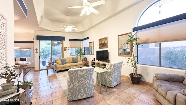 tiled living room with a raised ceiling, ceiling fan, and a healthy amount of sunlight