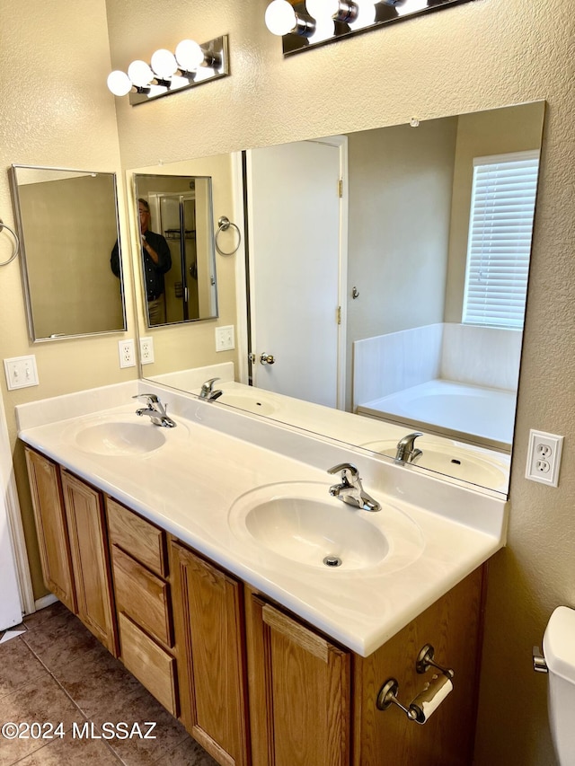 bathroom featuring tile patterned flooring, vanity, toilet, and a tub