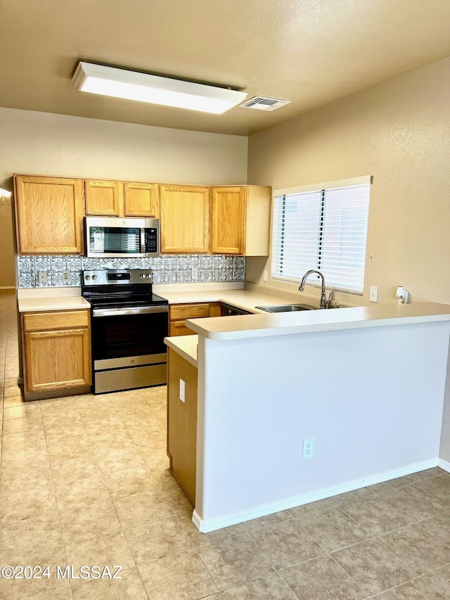 kitchen with sink, tasteful backsplash, kitchen peninsula, light tile patterned floors, and appliances with stainless steel finishes