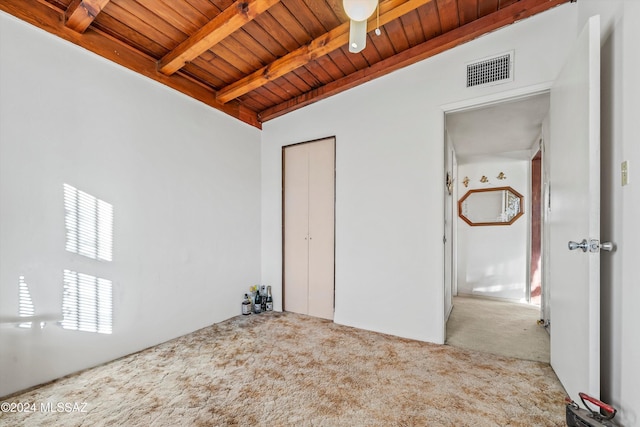 interior space with light carpet, a closet, beamed ceiling, and wooden ceiling