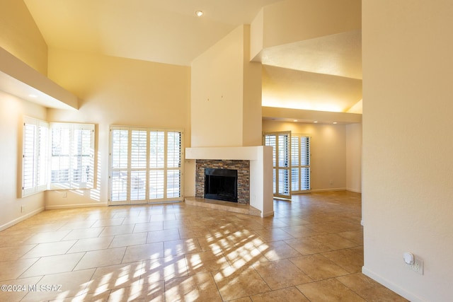 unfurnished living room with light tile patterned flooring, a stone fireplace, and high vaulted ceiling