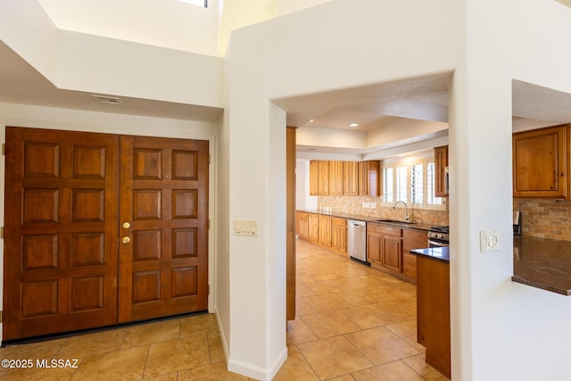 foyer entrance featuring light tile patterned floors, baseboards, and a towering ceiling