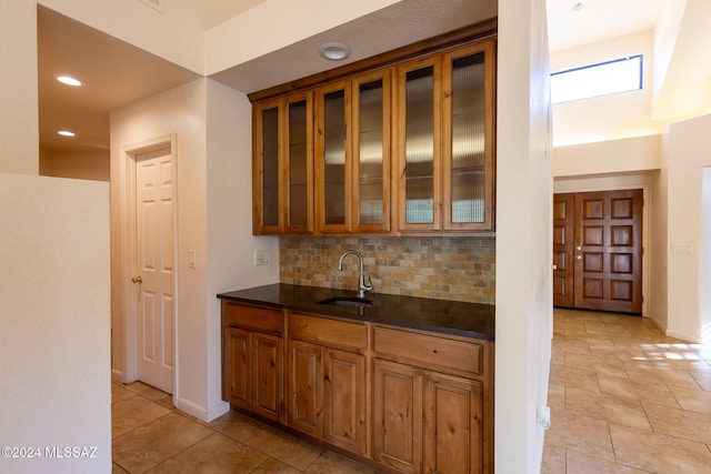 kitchen featuring backsplash, dark stone countertops, and sink