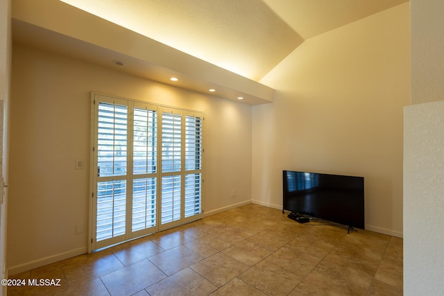 tiled empty room featuring vaulted ceiling