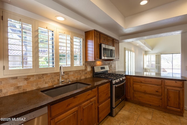 kitchen with brown cabinetry, recessed lighting, a sink, appliances with stainless steel finishes, and backsplash