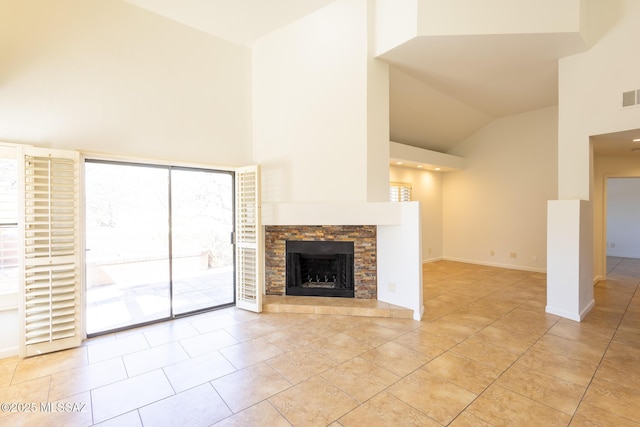 unfurnished living room featuring a stone fireplace, light tile patterned floors, visible vents, and high vaulted ceiling