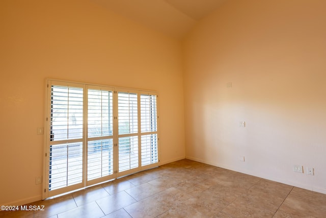 spare room featuring high vaulted ceiling and light tile patterned flooring