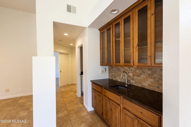 bar with light tile patterned floors, baseboards, visible vents, a sink, and decorative backsplash