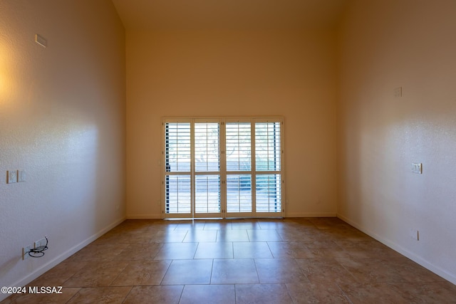 tiled empty room featuring a towering ceiling