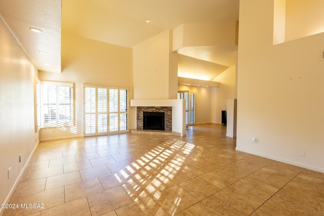 unfurnished living room with a textured ceiling, light tile patterned floors, a fireplace, and high vaulted ceiling