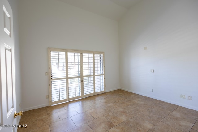 empty room featuring tile patterned flooring, high vaulted ceiling, and baseboards