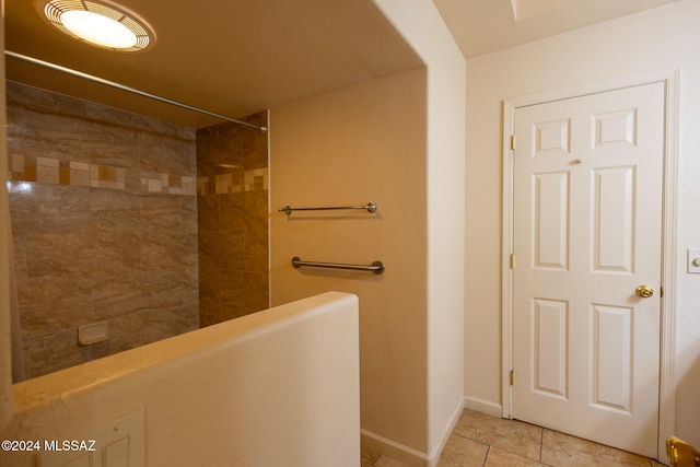 bathroom with a tile shower and tile patterned flooring