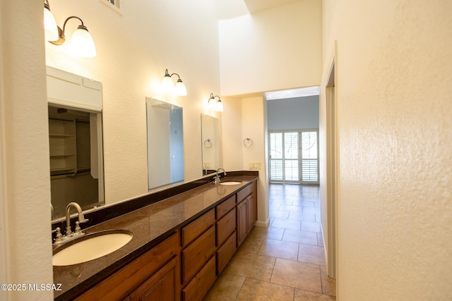 bathroom featuring double vanity, tile patterned floors, a towering ceiling, and a sink