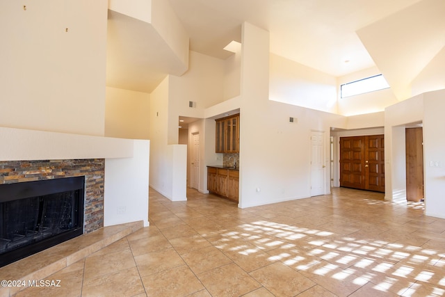 unfurnished living room featuring a fireplace, a towering ceiling, and light tile patterned flooring