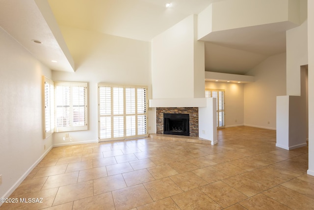 unfurnished living room with light tile patterned floors, a fireplace, high vaulted ceiling, and baseboards