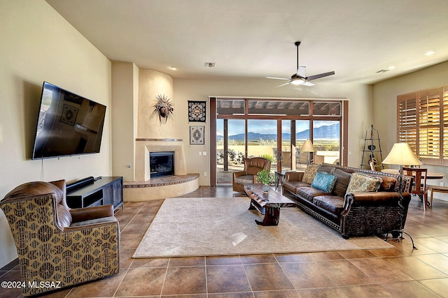 living room with a large fireplace, tile patterned floors, and ceiling fan