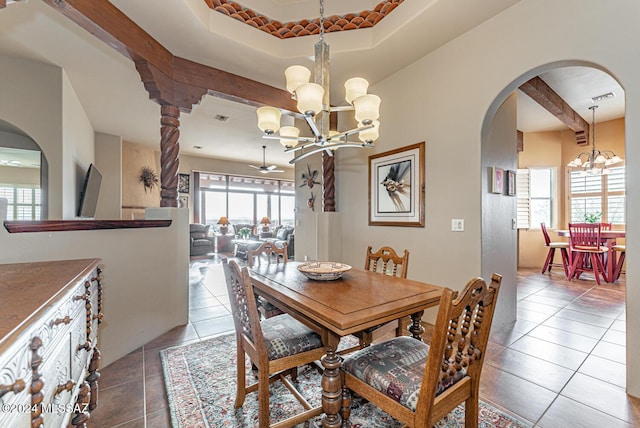 dining space featuring a tray ceiling, an inviting chandelier, a wealth of natural light, and light tile patterned flooring