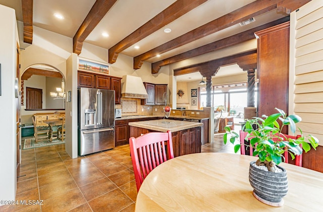 kitchen with beam ceiling, a center island, stainless steel appliances, tasteful backsplash, and custom range hood