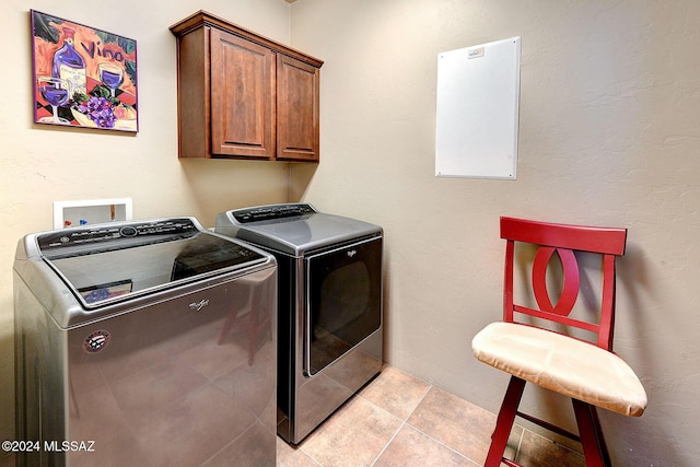 laundry room featuring cabinets, separate washer and dryer, and light tile patterned flooring