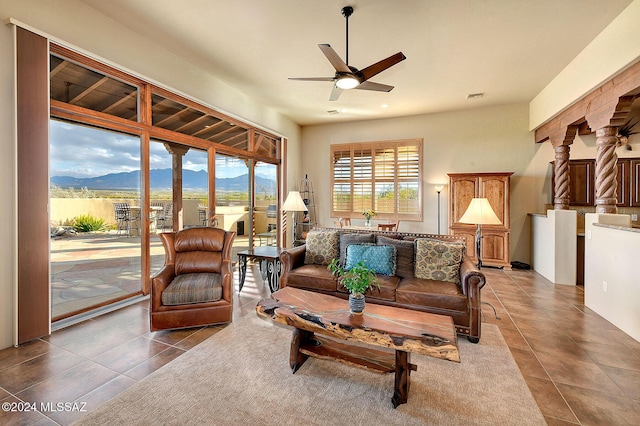 living room featuring a mountain view, dark tile patterned flooring, and ceiling fan