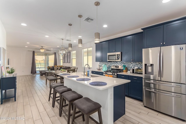 kitchen featuring pendant lighting, a kitchen island with sink, ceiling fan, blue cabinetry, and stainless steel appliances