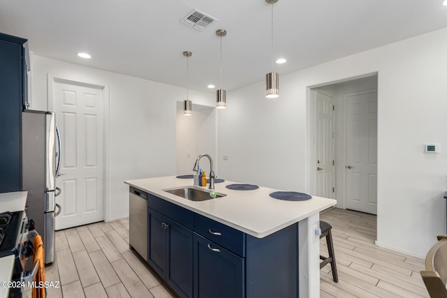 kitchen with blue cabinets, a sink, hanging light fixtures, light countertops, and an island with sink