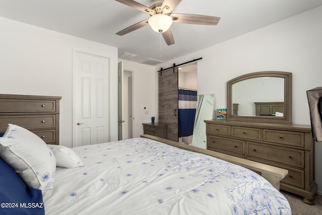 carpeted bedroom featuring ceiling fan and a barn door