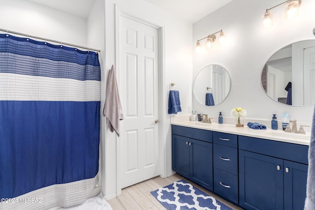 full bathroom with double vanity, wood finished floors, and a sink