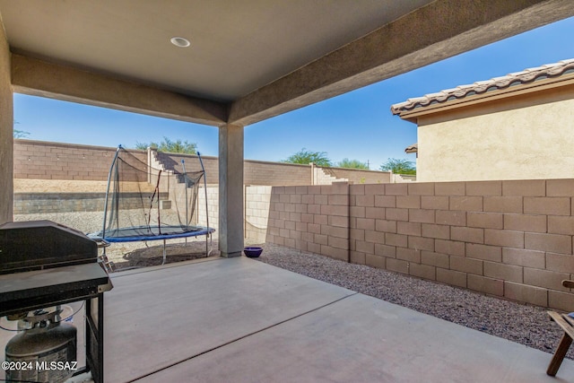 view of patio / terrace featuring a trampoline, a fenced backyard, and grilling area