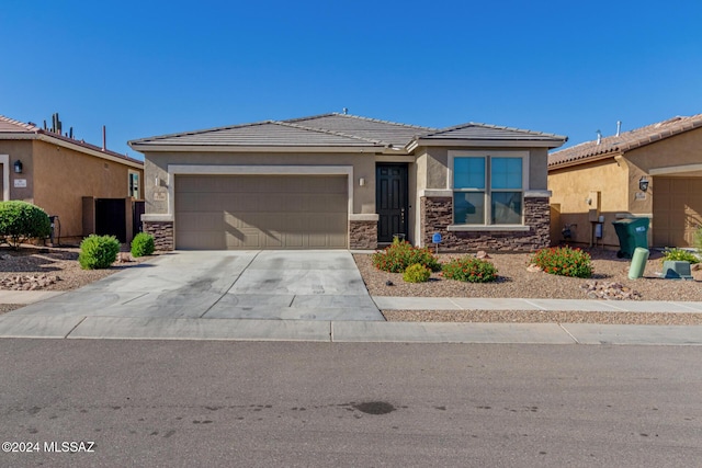 view of front of property with a tile roof, stucco siding, an attached garage, stone siding, and driveway