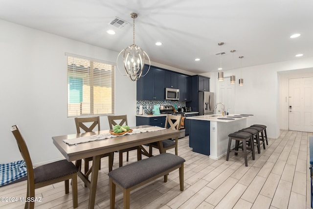 dining space featuring a notable chandelier, light hardwood / wood-style floors, and sink