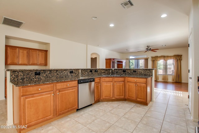 kitchen with ceiling fan, sink, dark stone countertops, dishwasher, and light tile patterned flooring